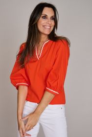 Oranje bloes met witte zigzag boord aan hals en mouwen Léonie de Paris